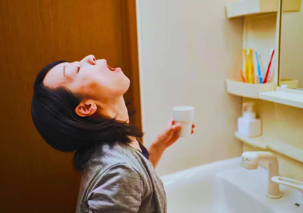 Hình ảnh người phụ nữ đang sút miệng bằng nước muối để phòng bệnh đau họng